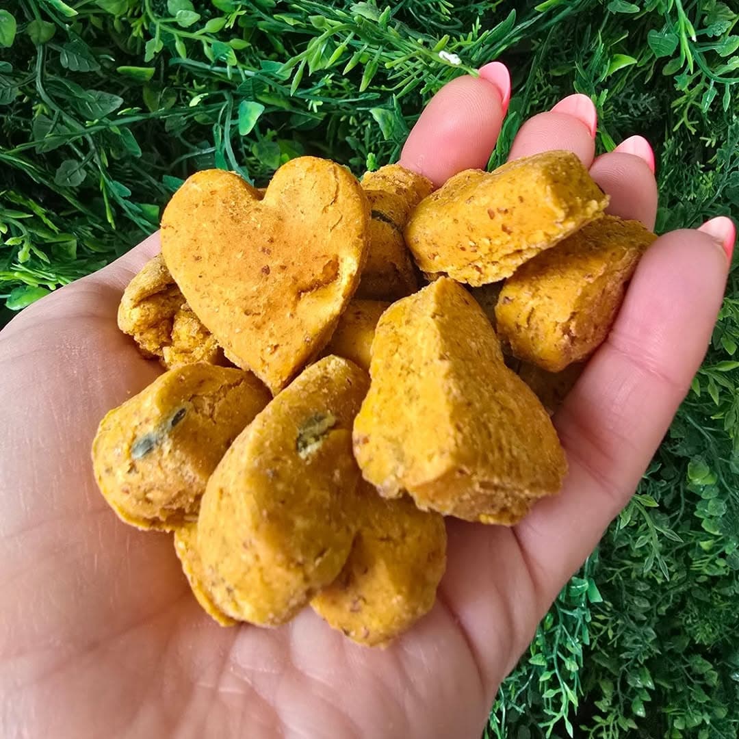 Two heart-shaped biscuits held against a green hedge
